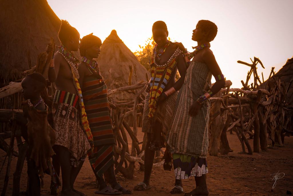Eine Gruppe Frauen im Gegenlicht der Abendsonne zwischen Hütten