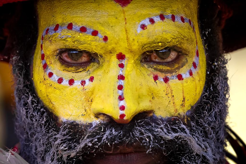 Sadhu mit gelb bemaltem Gesicht, roten Punkten um die Augen und grauem Bart