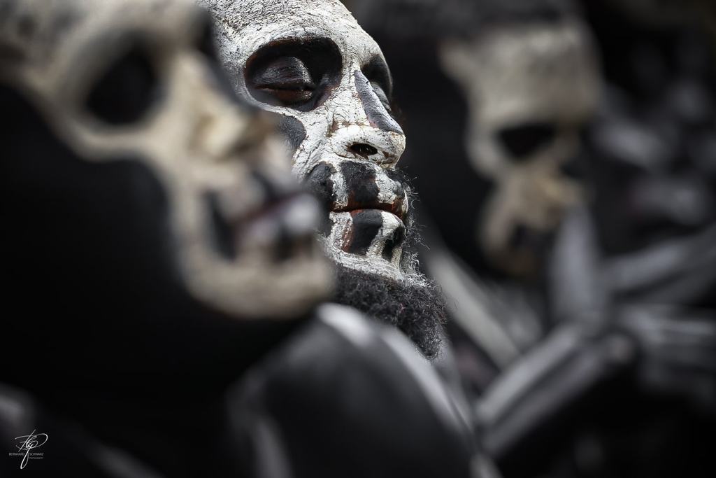 Tänzer mit als Totenkopf bemalten Gesichtern, einer davon scharf im Vordergrund