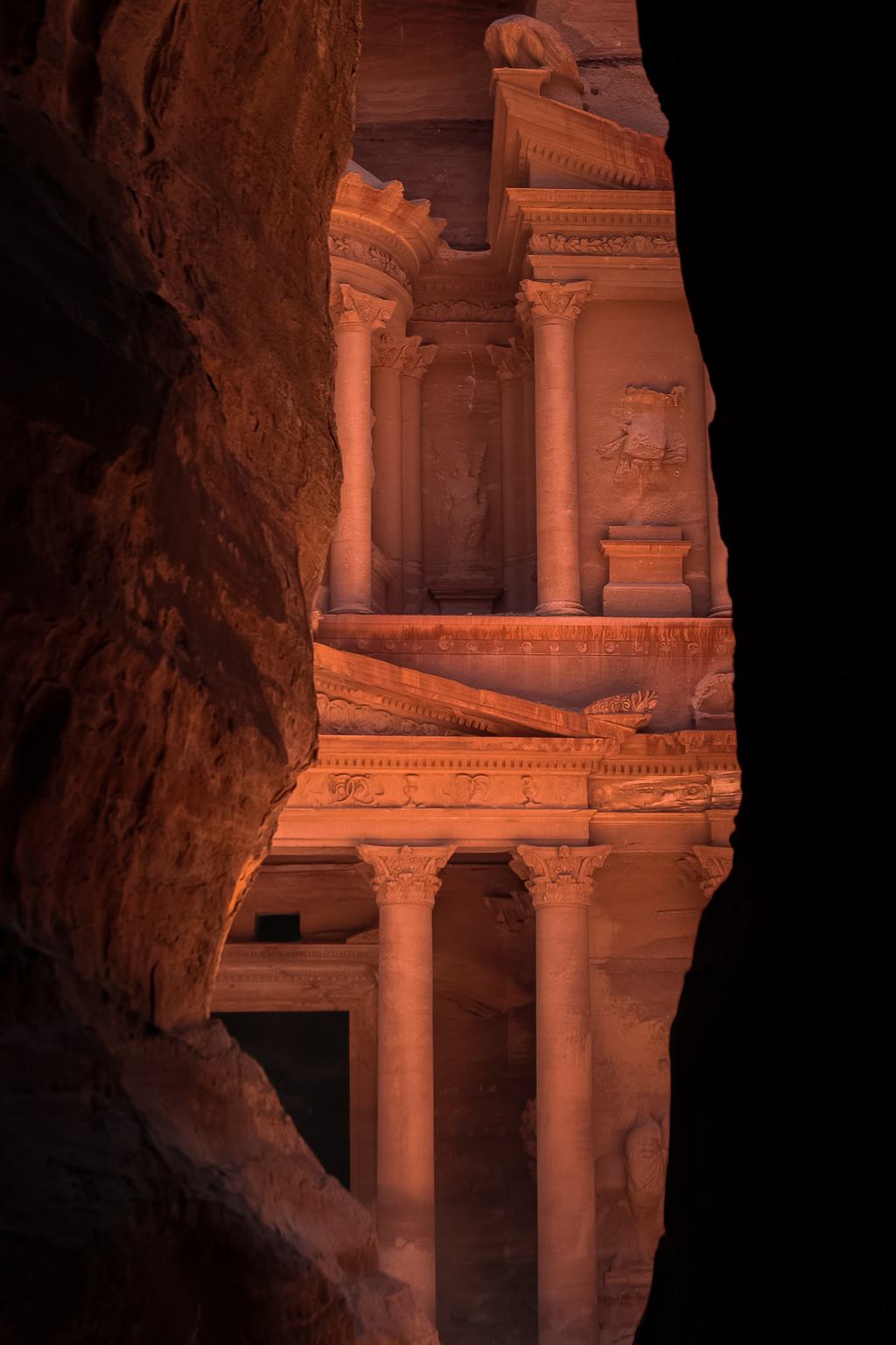Die Fassade eines aus dem Felsen geschlagenen Grabmals, durch eine Schluchtöffnung gesehen