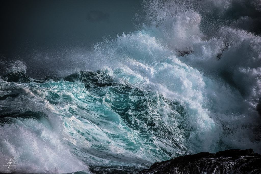 Eine brechende Welle über dunklem Fels